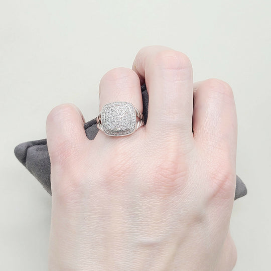 Hand wearing a silver ring with a textured band on a neutral background