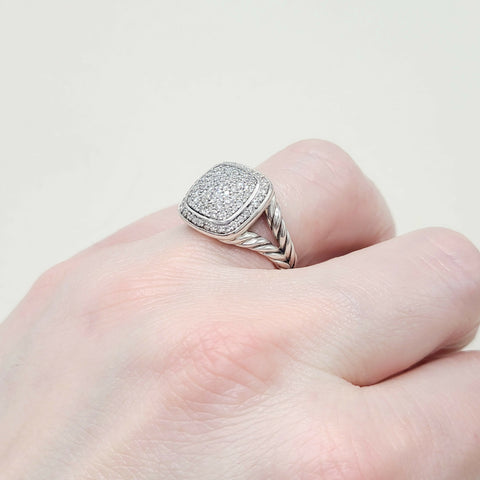 Silver ring with diamond accents on a finger against a light background
