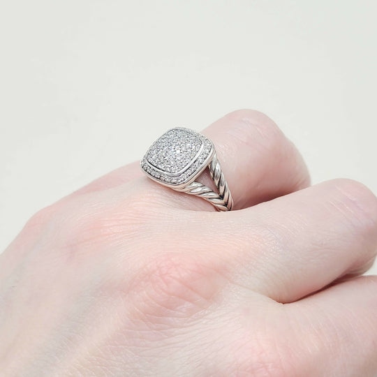 Silver ring with diamond accents on a finger against a light background