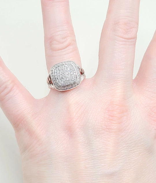 Silver ring with gemstones on a hand against a white background