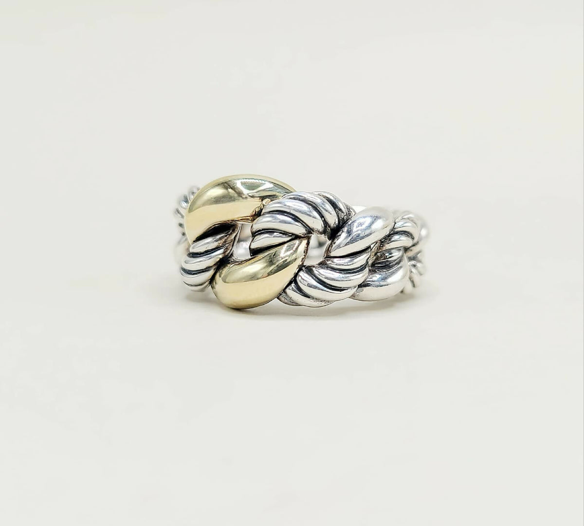 Silver and gold braided ring on a light gray background