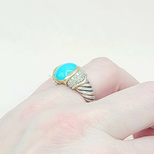 Ring with turquoise stone and gold band on a finger against a light background