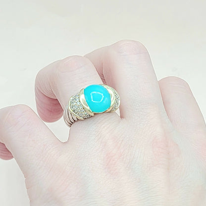 Turquoise ring with gold accents on a finger against a light background