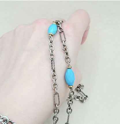 Silver chain bracelet with turquoise beads on a hand against a light background