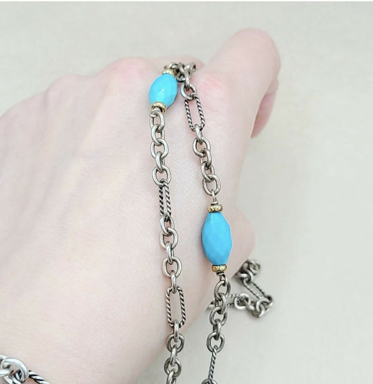 Silver chain bracelet with turquoise beads on a hand against a light background