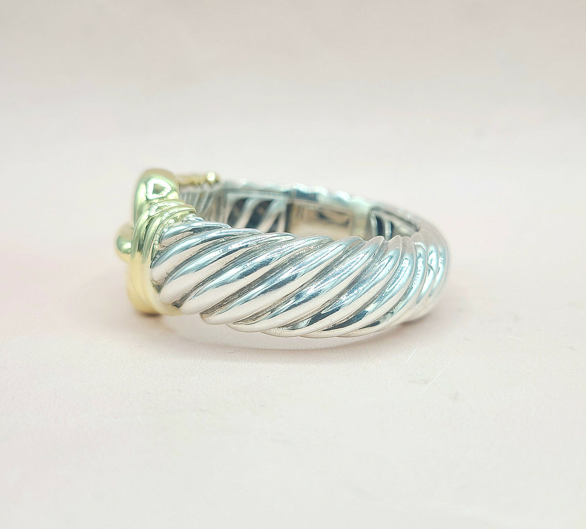 Silver ring with a textured design on a light pink background
