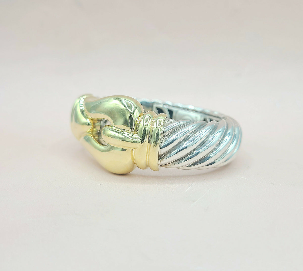 Two-tone bracelet with gold and silver design on a light pink background