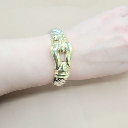 Gold bracelet on a wrist against a neutral background