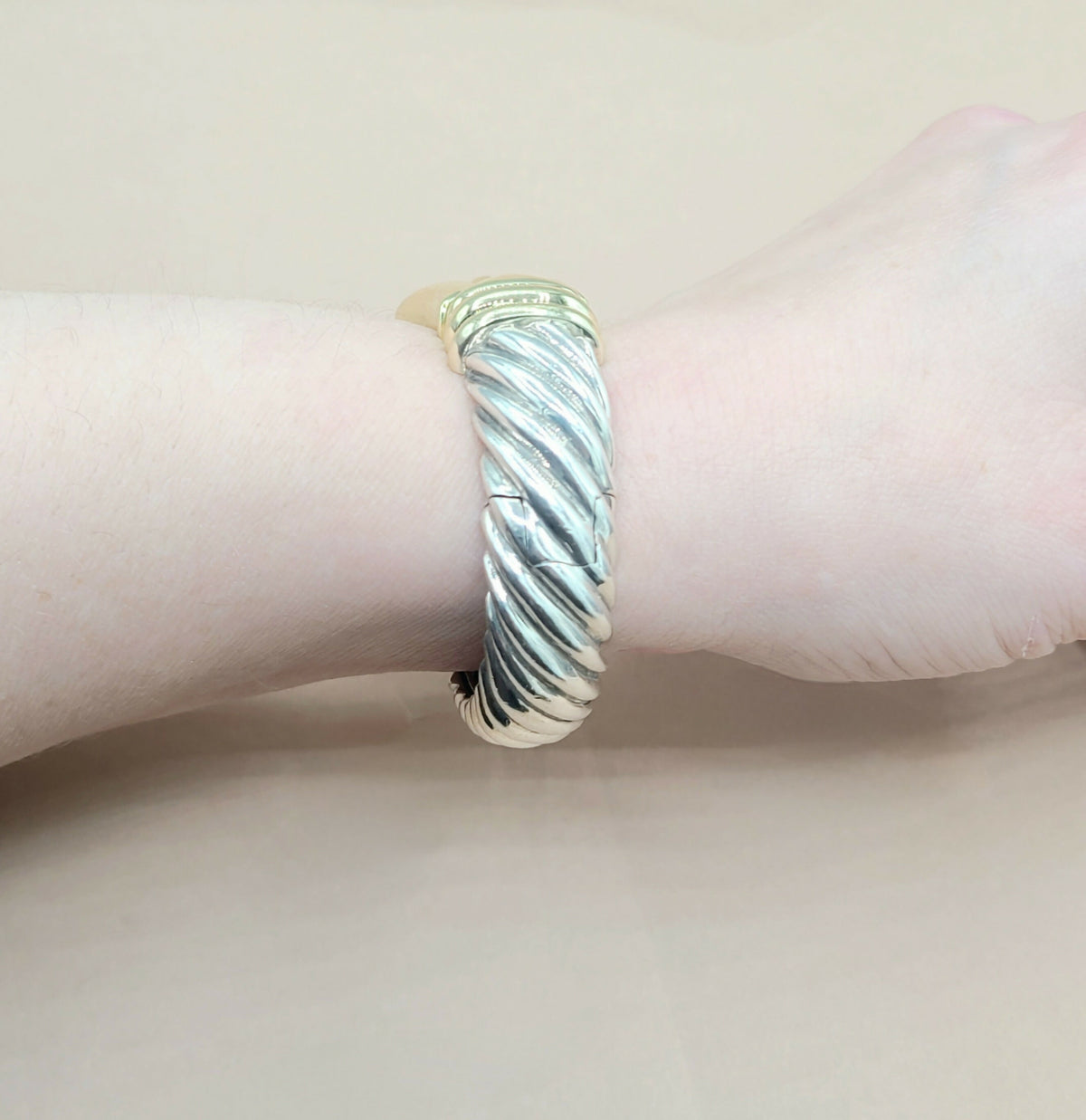 Silver bracelet on a wrist with a light pink background