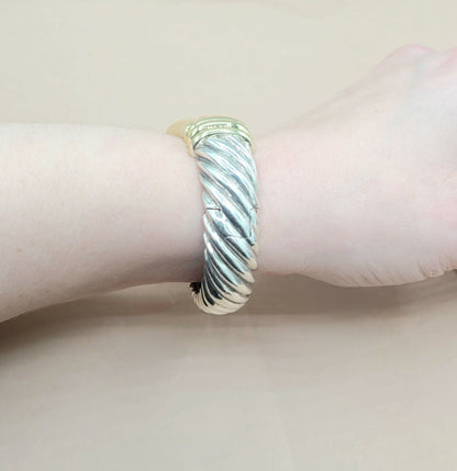 Silver bracelet on a wrist with a light pink background