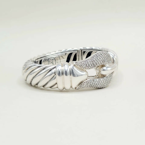 Silver ring with a textured band and diamond-studded bow on a white background