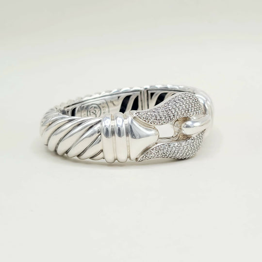 Silver ring with a textured band and diamond-studded bow on a white background