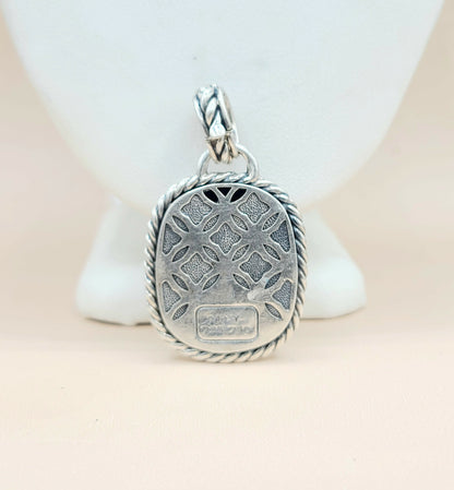 Silver pendant with intricate design on a light background