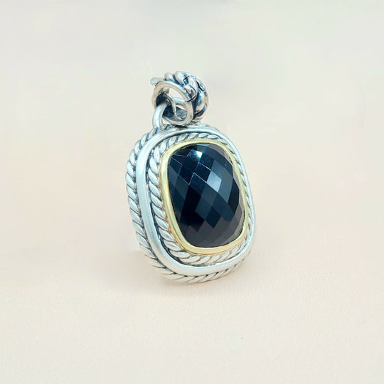 Silver pendant with a blue gemstone on a beige background