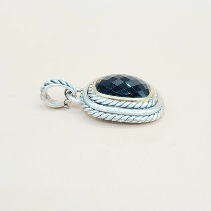 Silver pendant with a black stone on a light beige background