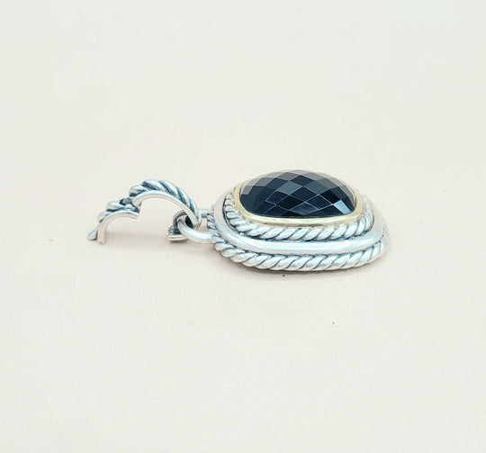 Silver pendant with a black gemstone on a light beige background