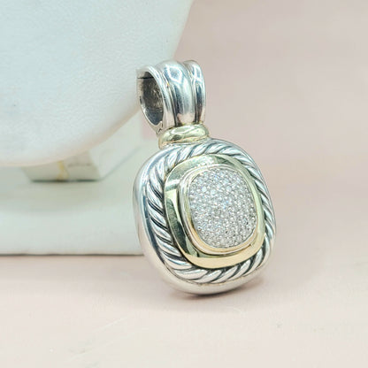 Silver and gold pendant with intricate design on a light background