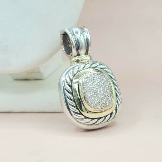 Silver and gold pendant with intricate design on a light background