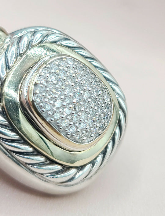 Silver pendant with diamond-studded center on a light pink background