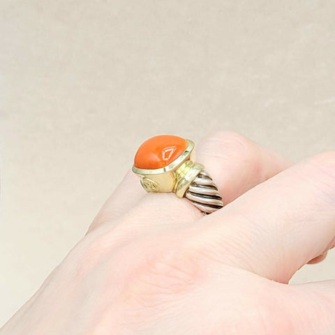 Gold ring with a red stone on a beige background