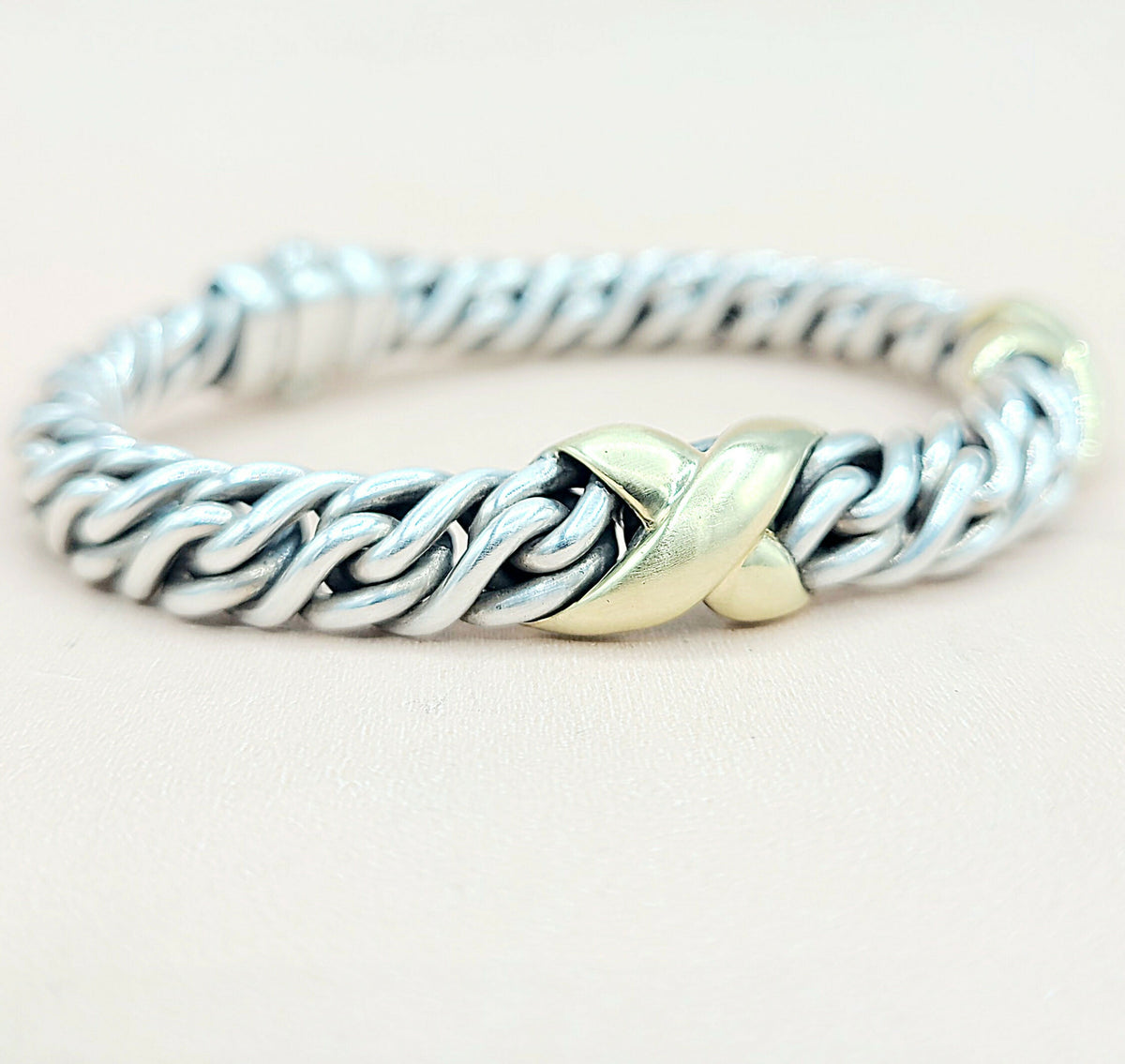 Silver and gold braided ring on a light background