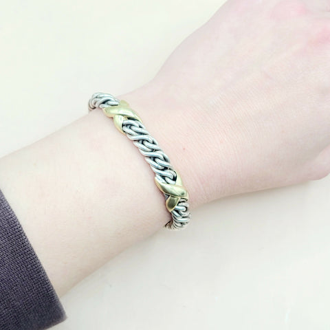 Bracelet with braided design on a wrist against a light background