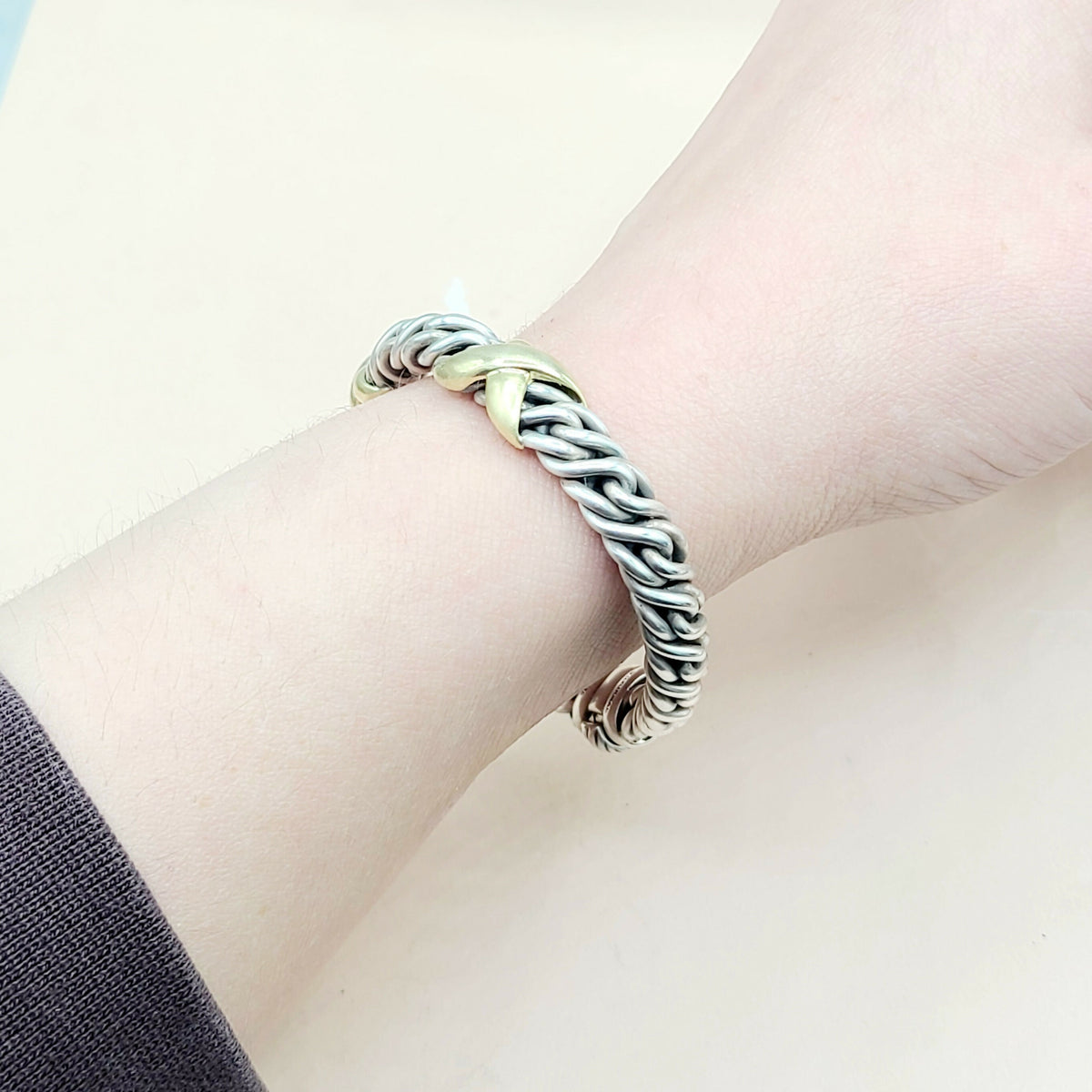 Silver braided bracelet on a wrist with a light background