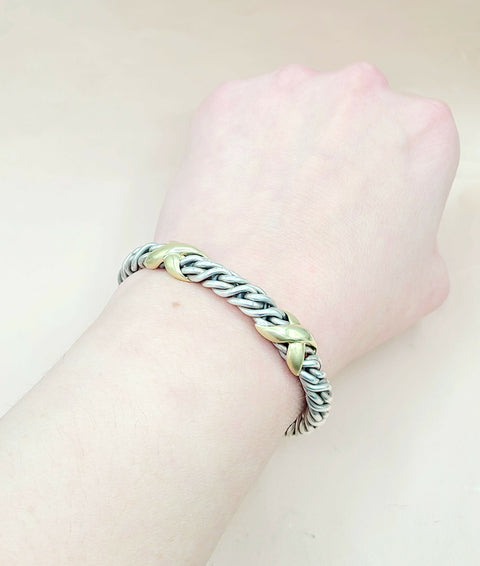 Bracelet with braided design on a wrist against a plain background