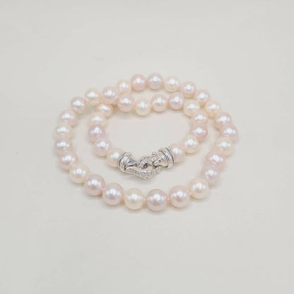 Pearl necklace with a silver clasp on a light gray background