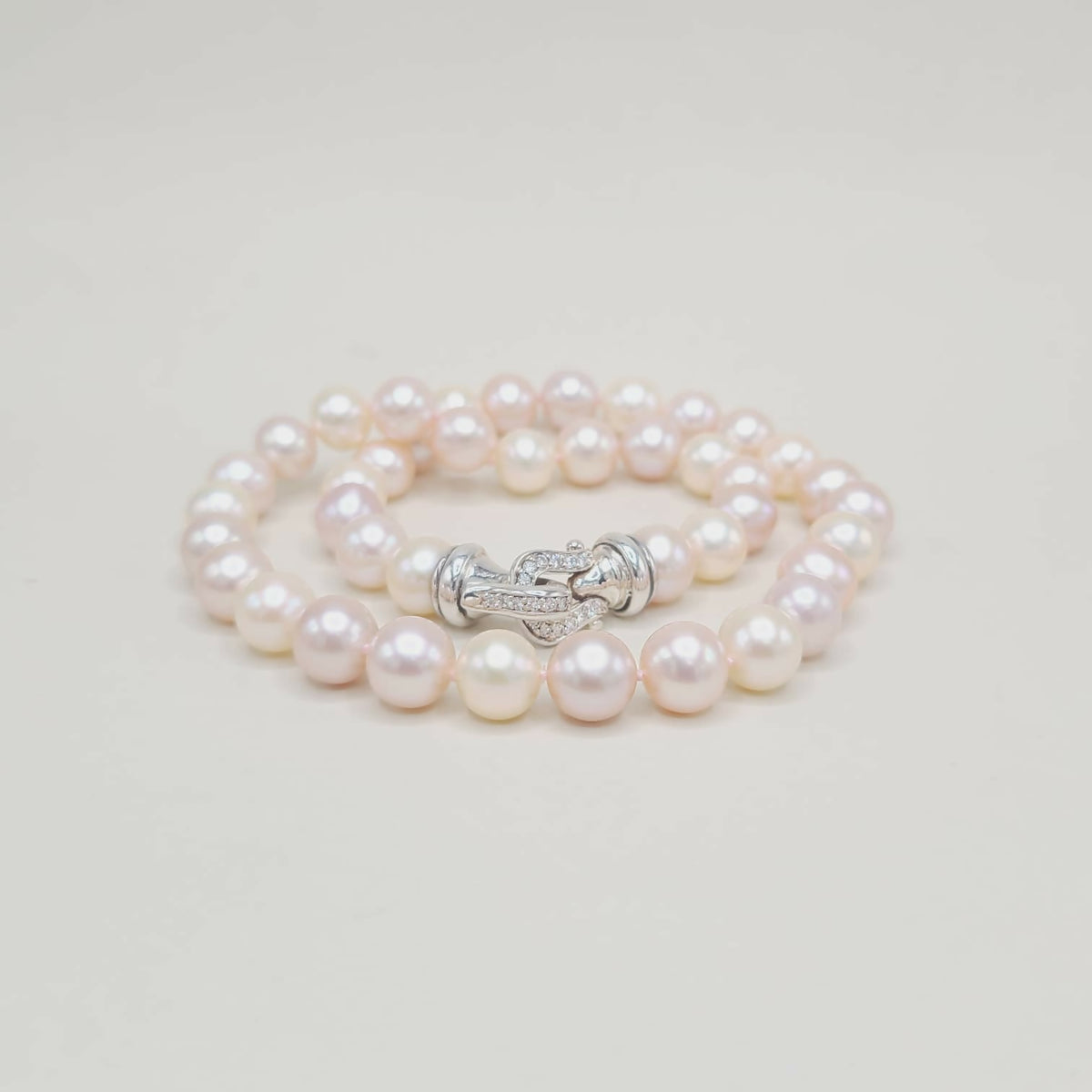 Pearl bracelet with a silver clasp on a light gray background