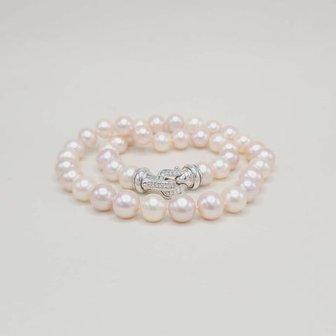 Pearl bracelet with a silver clasp on a light gray background