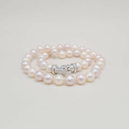 Pearl bracelet with a silver clasp on a light gray background