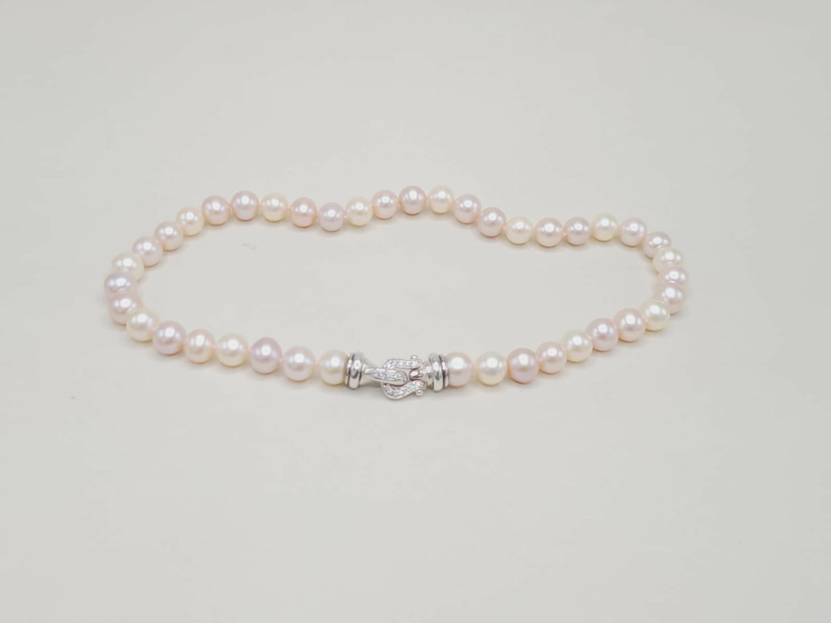 Pearl bracelet with a silver clasp on a light gray background
