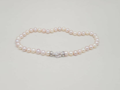Pearl bracelet with a silver clasp on a light gray background