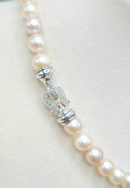 Pearl necklace with silver clasp on a light background