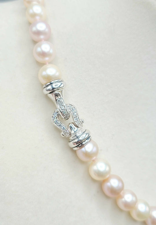 Pearl necklace with silver clasp on a light background
