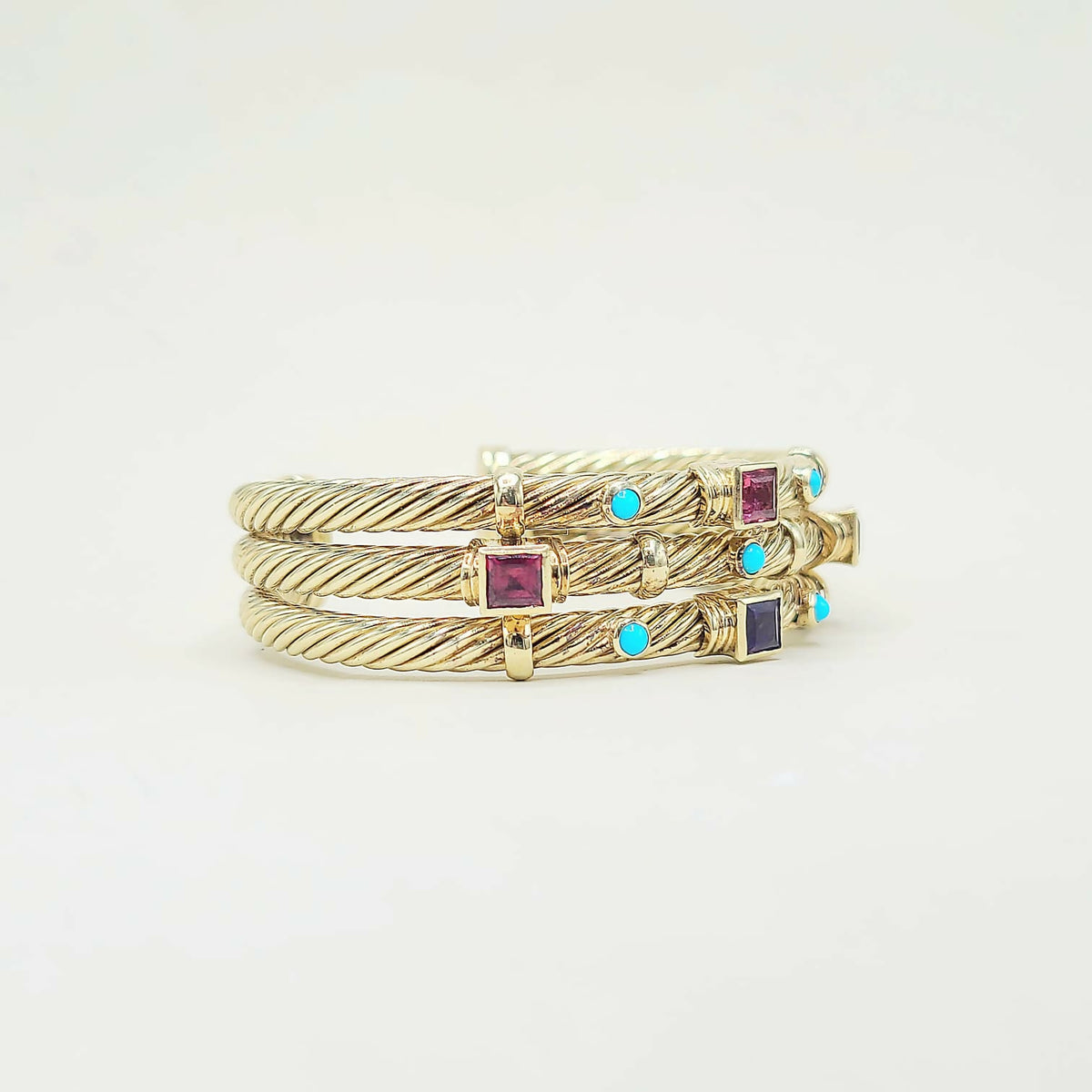 Three gold rings with gemstones on a light gray background