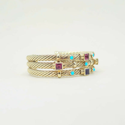Three gold rings with gemstones on a light gray background