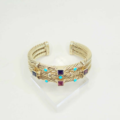 Gold bracelet with embedded gemstones on a white background