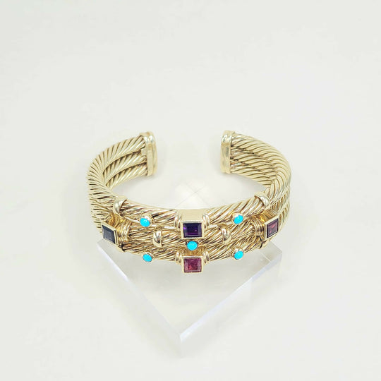 Gold bracelet with embedded gemstones on a white background