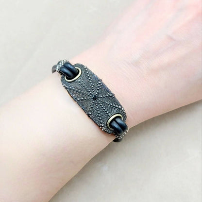 Black textured bracelet on a wrist against a light background