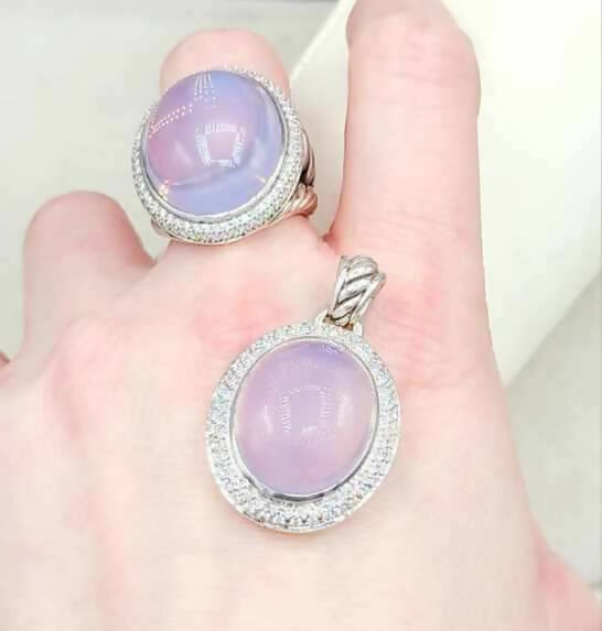 Ring and pendant with purple gemstones on a hand against a white background