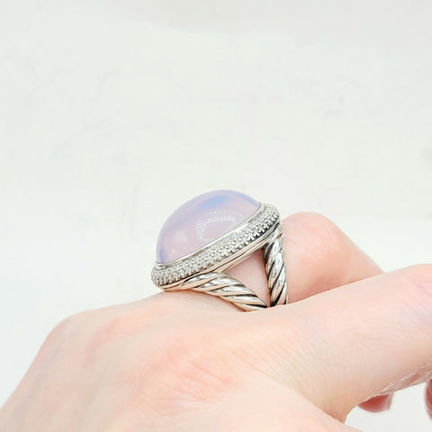 Ring with a large gemstone on a hand against a light background