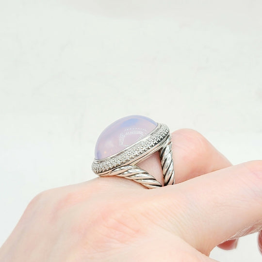 Ring with a large gemstone on a hand against a light background