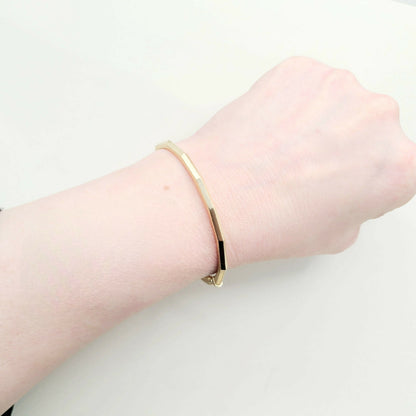 Gold bracelet on a wrist against a white background
