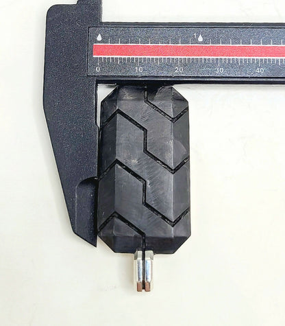 Close-up of a black tire tread being measured with a caliper on a white background