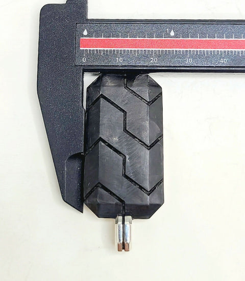 Close-up of a black tire tread being measured with a caliper on a white background