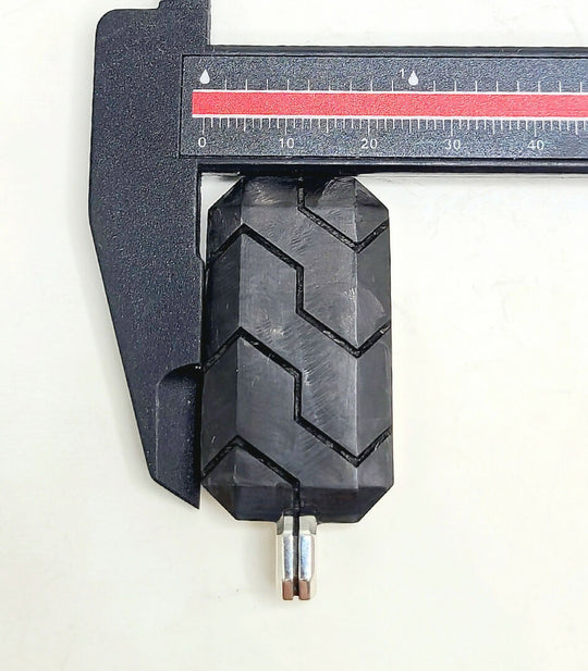 Close-up of a black tire tread being measured with a caliper on a white background