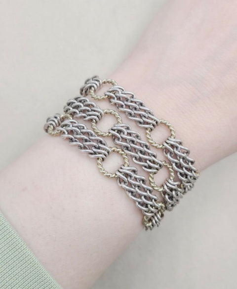 Silver chain bracelet on a wrist against a light background