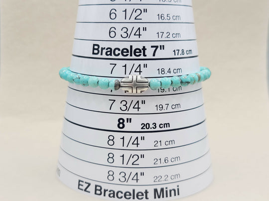 Turquoise beaded bracelet on a measuring cone with size markings.
